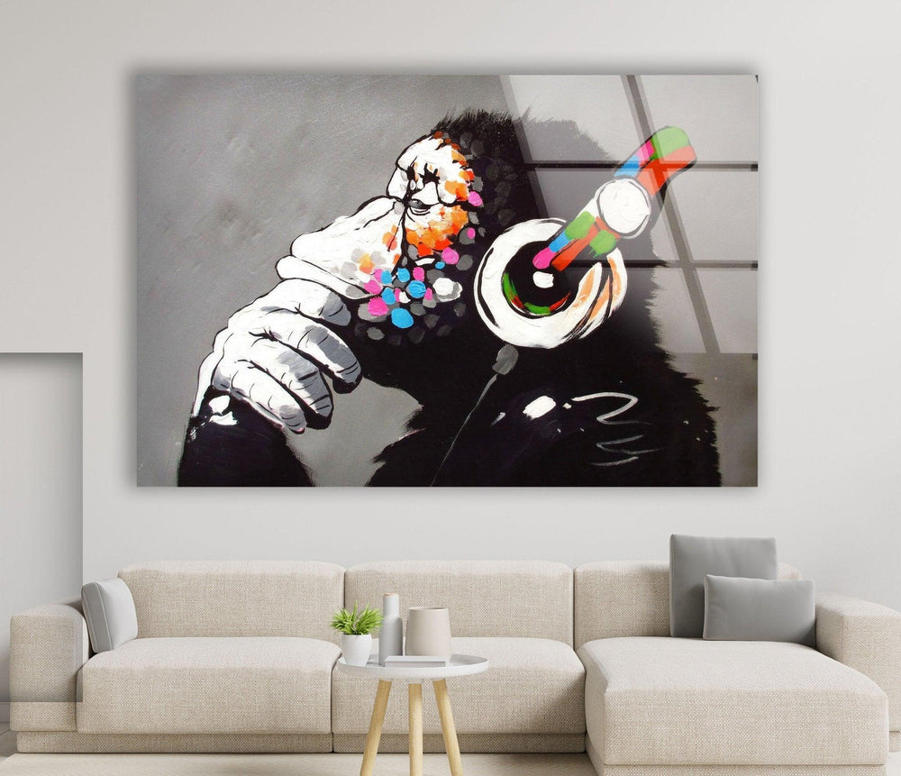 Banksy DJ Monkey Gorilla Thinking Tempered Glass Wall Art: A Glass painting of a monkey wearing headphones, printed on glass for durable, vibrant street art decor.