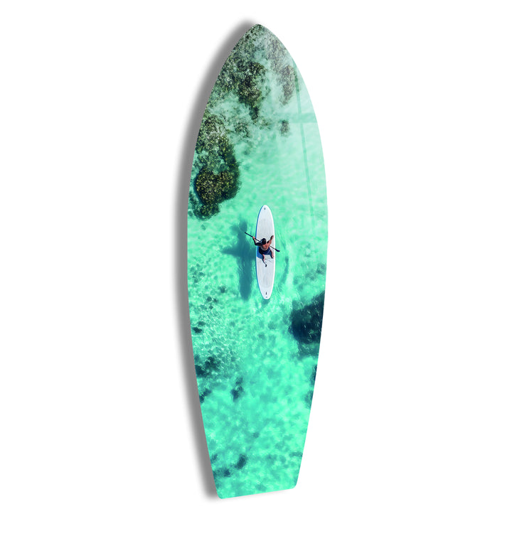 Aerial view of a paddleboarder gliding across crystal-clear turquoise waters, captured in stunning glass art.