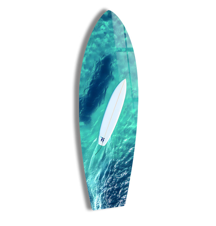 Surfer paddling through crystal-clear waters, captured in stunning aerial glass wall art.
