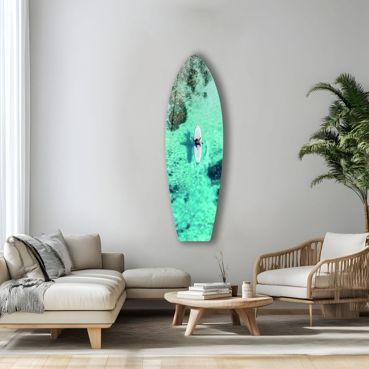 Stunning aerial shot of a paddleboarder in crystal-clear waters, captured in vivid glass art for beach lovers.
