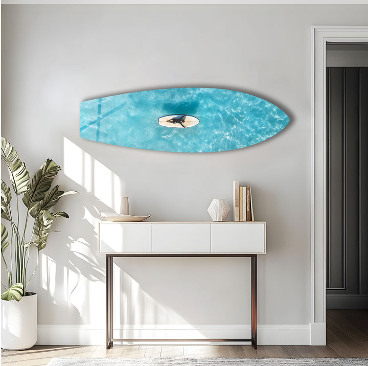 Surfer in the midst of calm, crystal-clear waters, captured in breathtaking aerial glass wall art.
