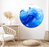 a living room with a white chair and a blue circular painting on the wall